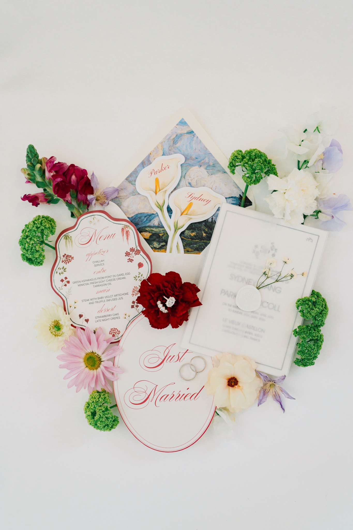 A wedding invitation suite laid flat with foliage and ribbon